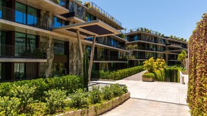 A modern multi-story building with balconies, a central courtyard, and lush greenery. - Private Heated Pool • Garden • Gym • Near the Sea (Funchal)