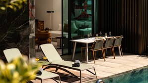 A modern outdoor dining area with a pool, lounge chairs, and a table set for a meal. - Private Heated Pool • Garden • Gym • Near the Sea (Funchal)