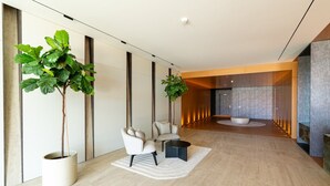 A modern lobby with a seating area, large potted plants, and a central water feature. - Private Heated Pool • Garden • Gym • Near the Sea (Funchal)