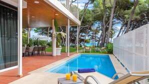 A poolside area with a pool, lounge chairs, and a table with drinks. - Villa Ocean - Beachfront Villa, Pool & Sea Views (Port d'Alcudia)