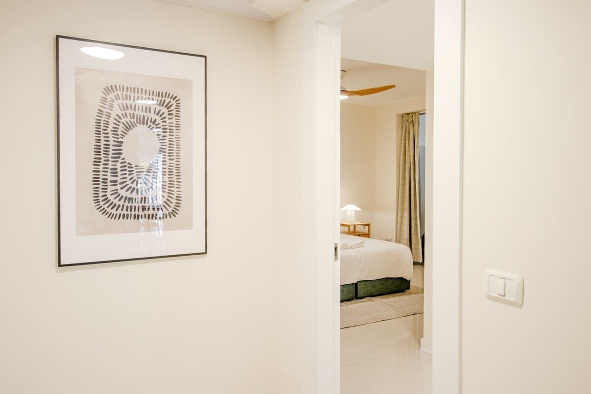 A hotel room with a bed, a nightstand, a lamp, and a framed abstract artwork on the wall.
