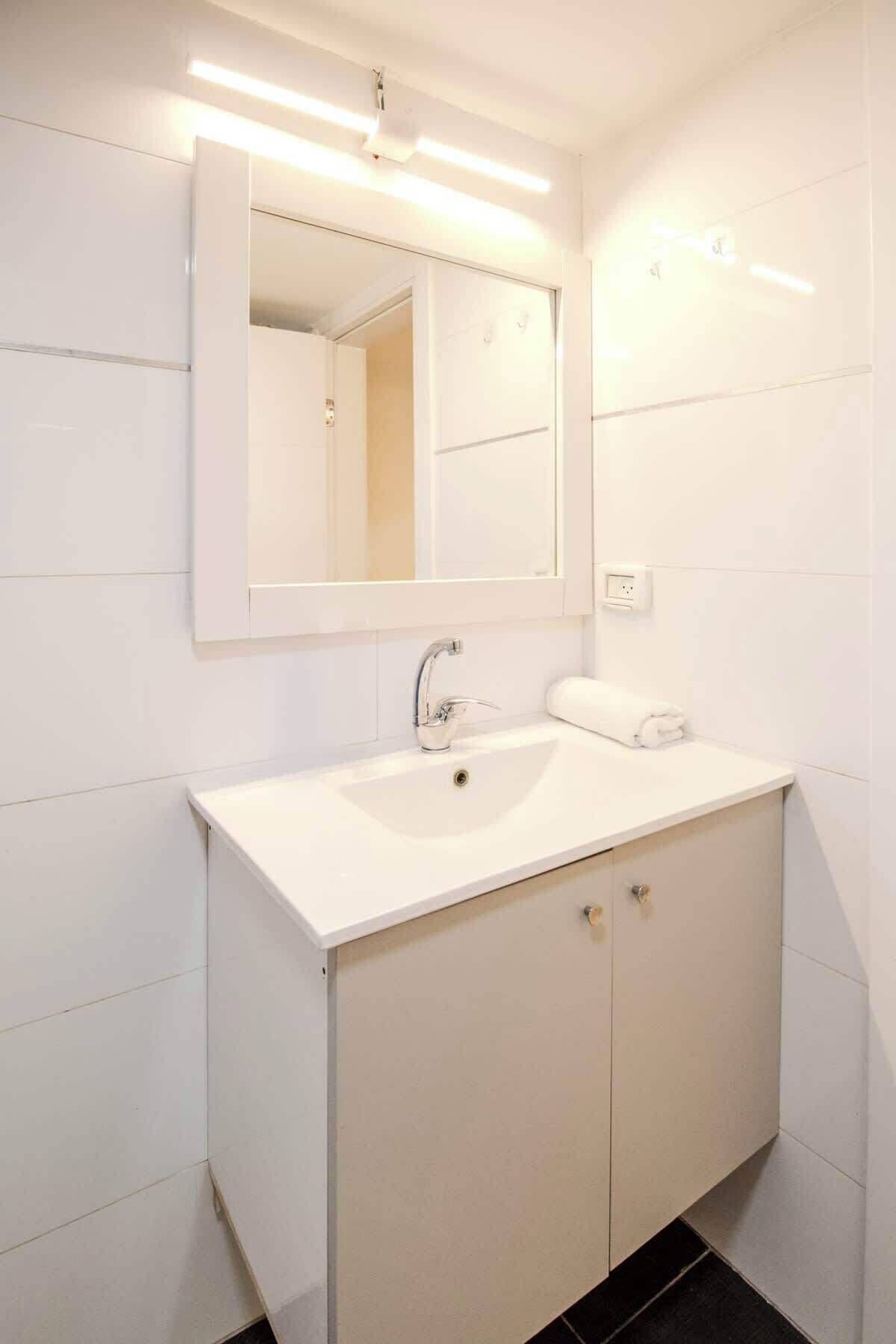 A modern bathroom with a white sink, a mirror, and a towel.