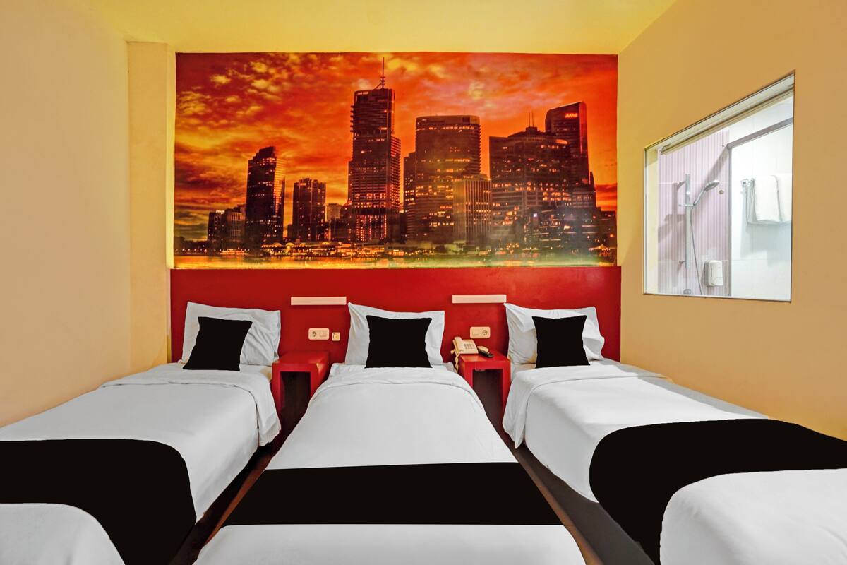Ein Hotelzimmer mit drei Betten, einem Stadtbild-Wandgemälde und einem Fenster mit Blick.