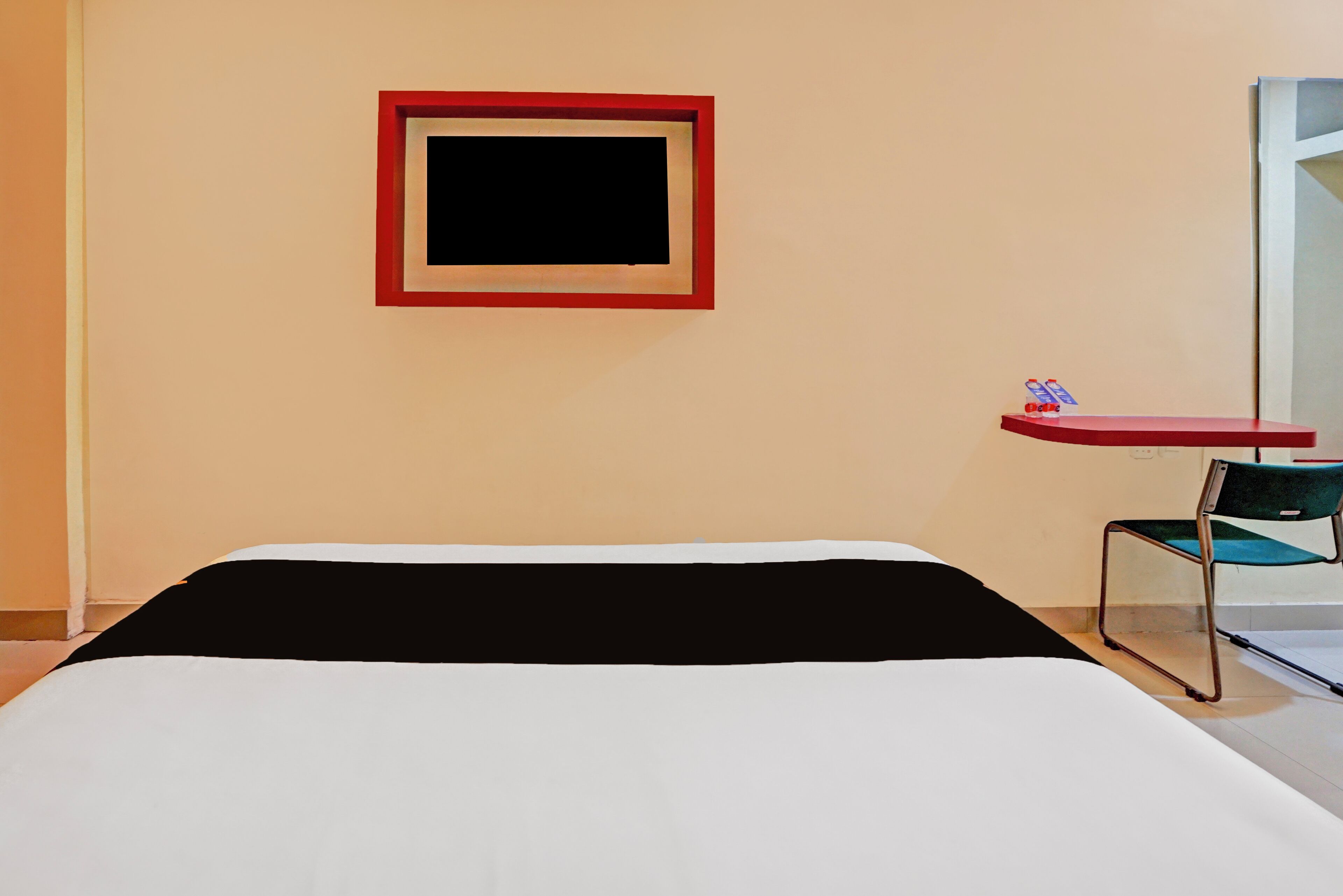 A hotel room with a bed, a small table, a chair, and a framed picture on the wall.