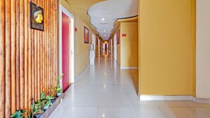 Un pasillo de hotel con paneles de madera en un lado, piso de baldosas y techo curvo.