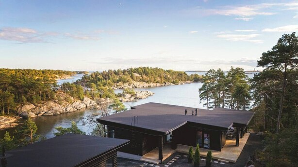 A modern cabin with a view of a lake and forest.