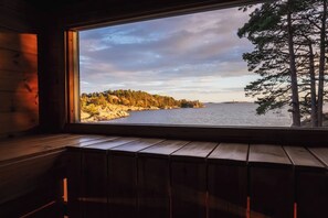 L’intérieur d’un chalet en bois, avec une grande fenêtre donnant sur une rive boisée.