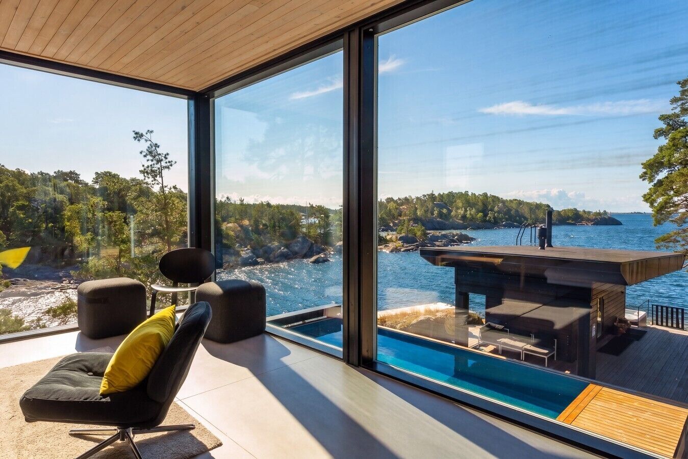 Ein modernes Zimmer mit großem Fenster, Blick auf einen Pool und eine malerische Felsenküste.