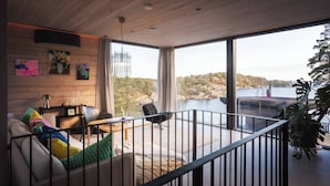 A modern interior with a wooden ceiling, large windows, a balcony, and a view of a body of water.