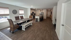 A spacious kitchen with modern appliances, a dining area with a large table and chairs, and a hallway leading to bedrooms. - Brand New Home with Open Floor Plan and Large Back Yard (Southport)