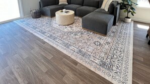 A modern living room with a sectional sofa, a round coffee table, and a patterned rug. - Brand New Home with Open Floor Plan and Large Back Yard (Southport)