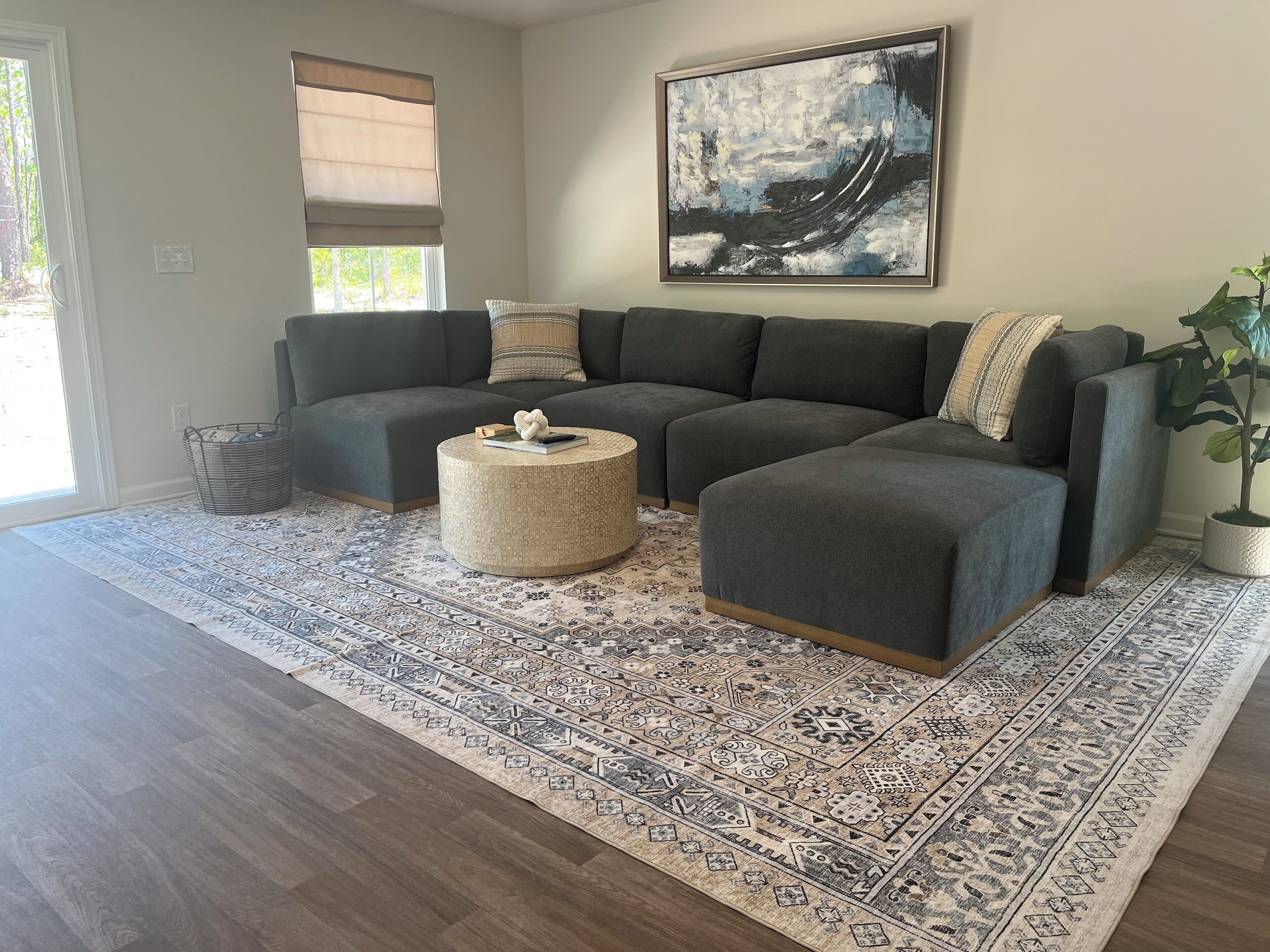 A modern living room with a sectional sofa, a round coffee table, and a patterned rug.
