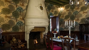 A dining area with a fireplace, wooden furniture, and a patterned wall. - Guest Room 'Rose' with Wi-Fi (Azay-sur-Cher)