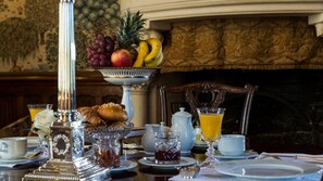 A breakfast setting with a fruit bowl, croissants, and a coffee pot on a table.