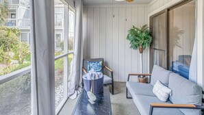 A balcony with a ceiling fan, a grey sofa, a chair with a blue cushion, and a potted plant. - 4 Mi to Beach: Unit w/ Pool Access in Little River (Little River)