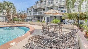 A pool area with lounge chairs and a table, surrounded by a low wall and palm trees. - 4 Mi to Beach: Unit w/ Pool Access in Little River (Little River)