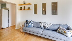 A living room with a grey sofa, wooden shelves with pictures, and a white wall. - Outdoor Adventure Haven - 15 Mi to Mount Shasta! (Weed)