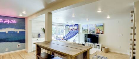 A spacious living area with a wooden table, a blue hammock, and a TV.