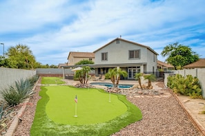 Una propiedad residencial con un césped cuidado, una piscina y una casa de techo plano.