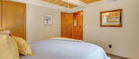 A bedroom with a large bed, wooden ceiling, and a ceiling fan.