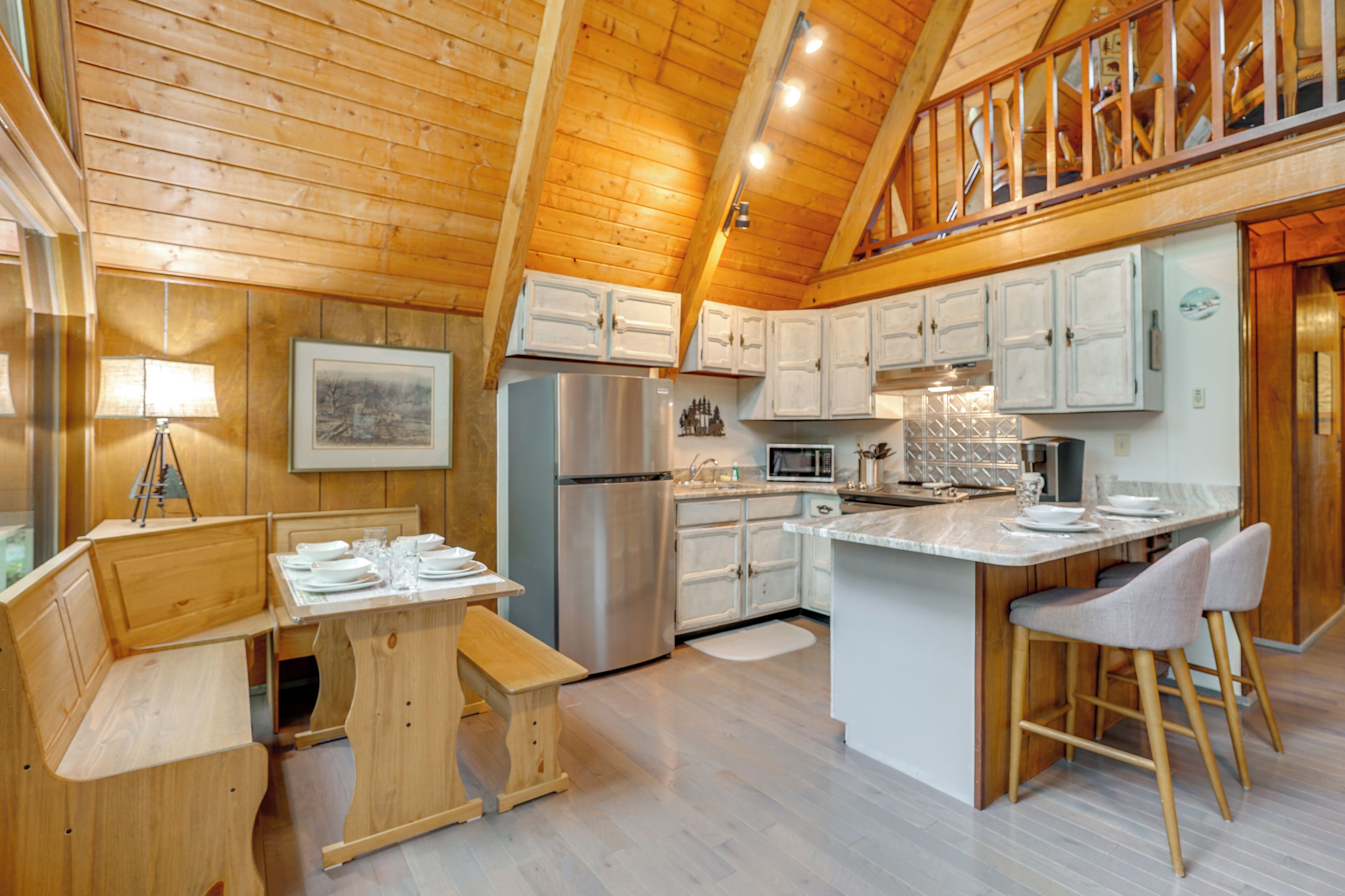 A wooden cabin interior with a kitchen featuring a refrigerator, microwave, and wooden cabinets.