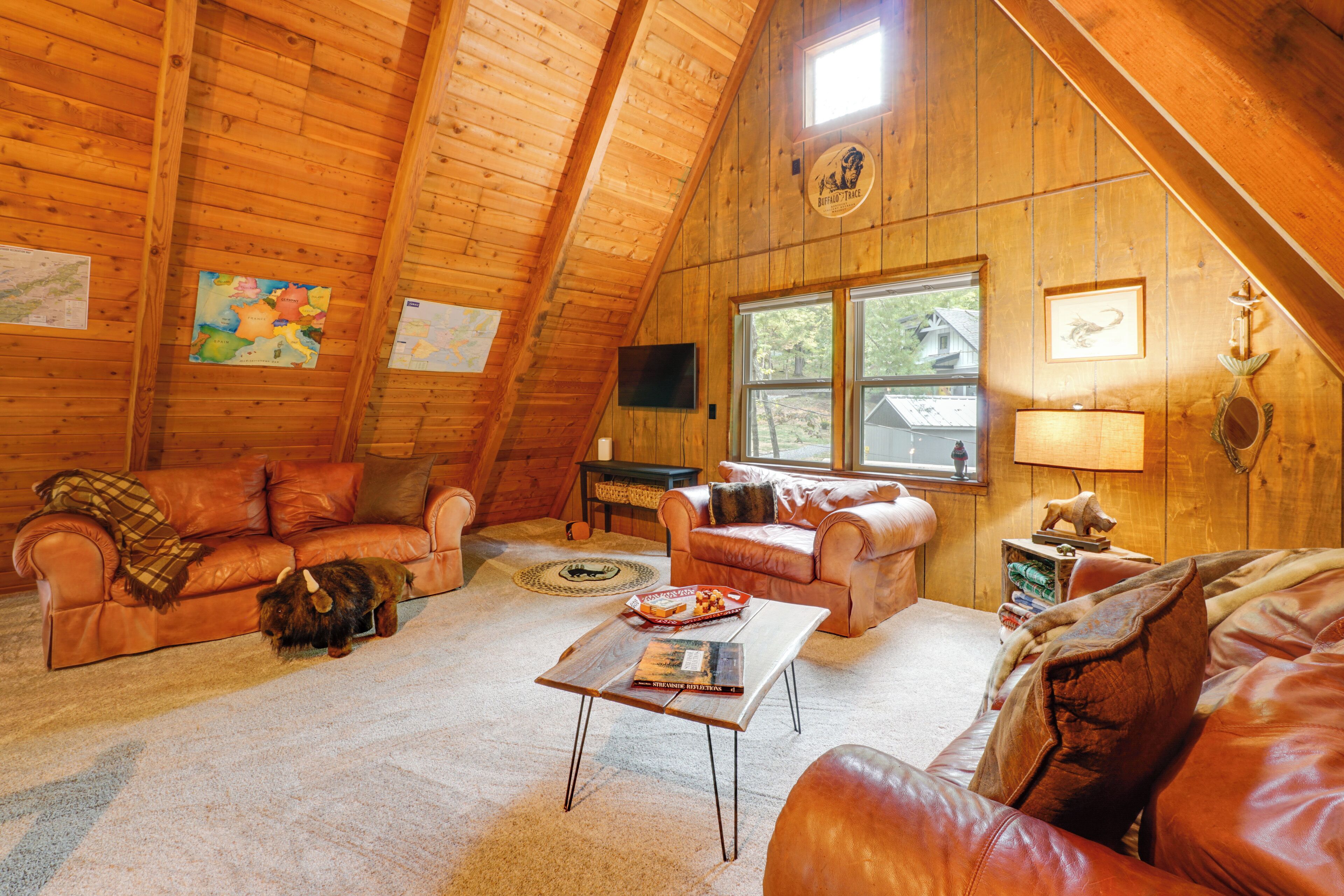 A cozy log cabin interior with two leather sofas, a coffee table, and a television.