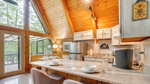 A modern kitchen with wooden beams, a large island with bar seating, and a view of the outdoors.