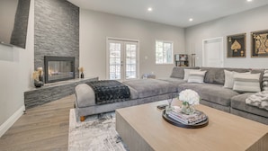 A modern living room with a stone fireplace, grey sofas, and a wooden coffee table.