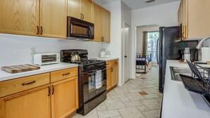 A kitchen with wooden cabinets, a microwave, a stove, and a sink. - Bike & Explore: Family Home in The Woodlands! (The Woodlands)