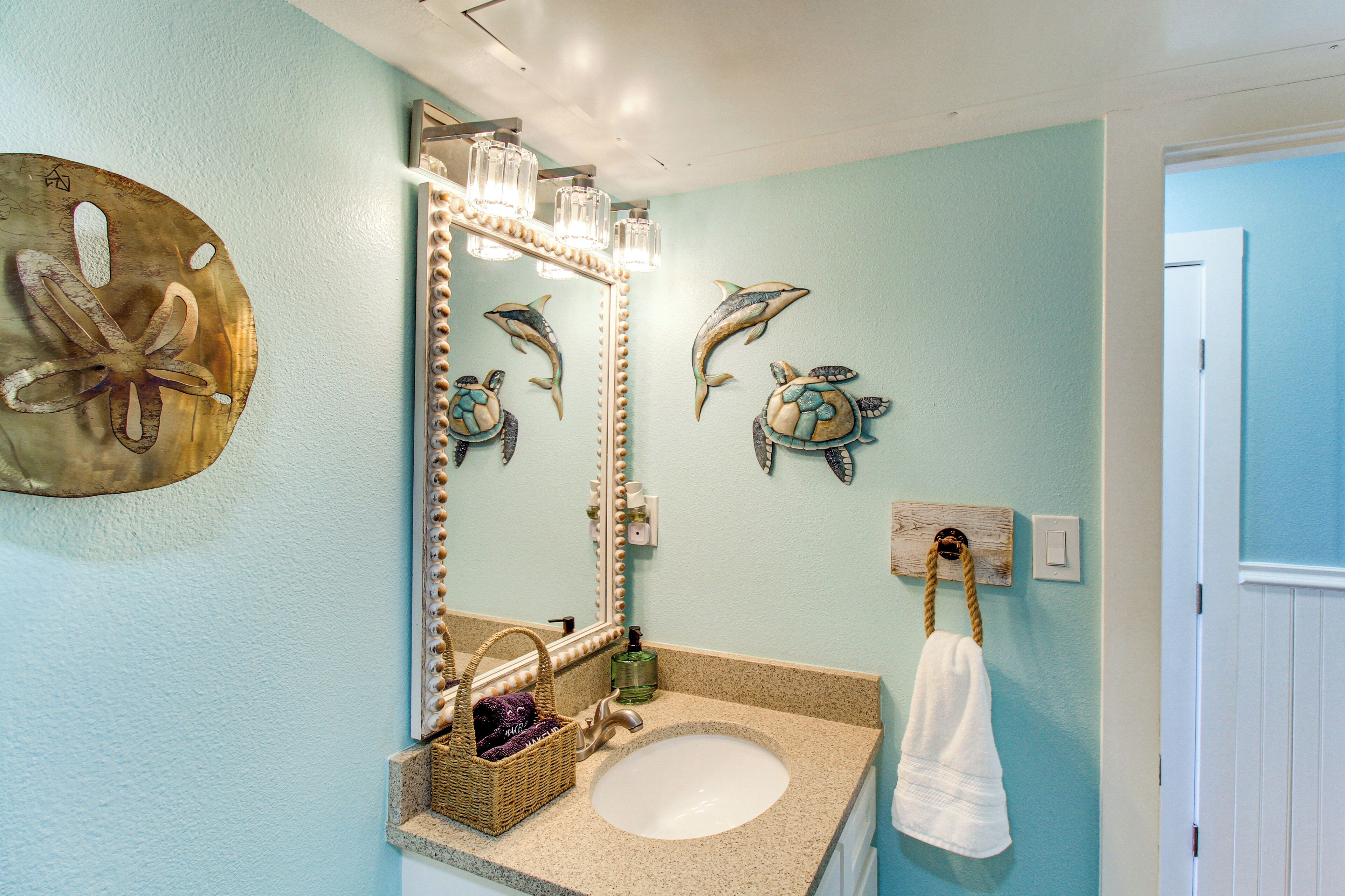 Une salle de bain avec un miroir rond, un lavabo, des éléments décoratifs sur les murs et un porte-serviettes.