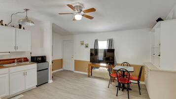 A compact kitchen with a dining area, a ceiling fan, and a TV.