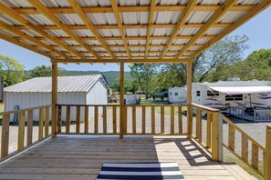 A wooden deck with a metal roof, overlooking a campsite with RVs and a small building. - Fish & Explore: Wooded Lake Guntersville Retreat (Langston)