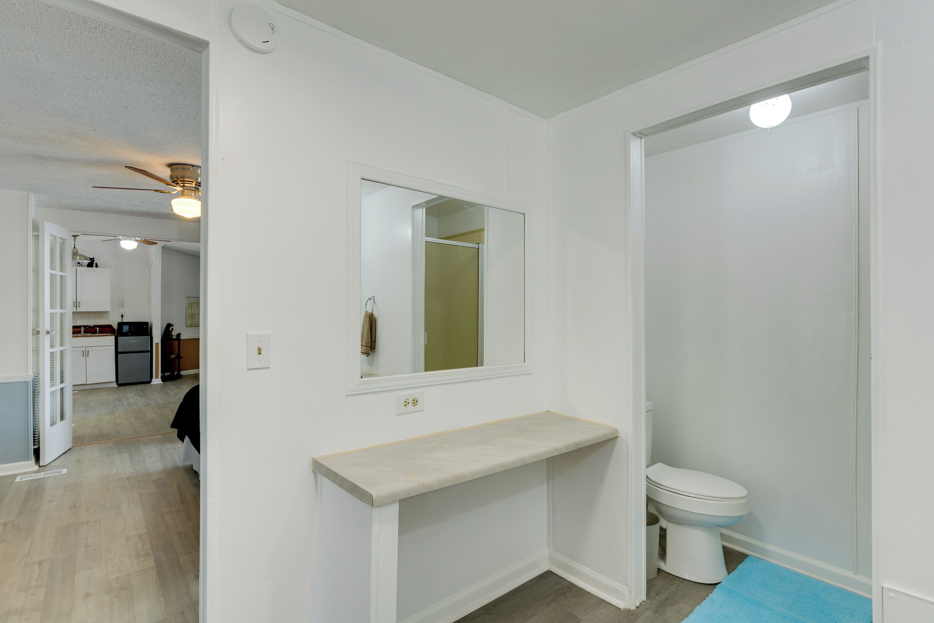 A bathroom with a toilet, a sink with a mirror, and a shower area.