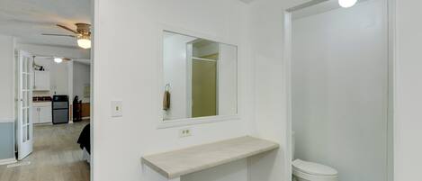 A bathroom with a toilet, a sink with a mirror, and a shower area.