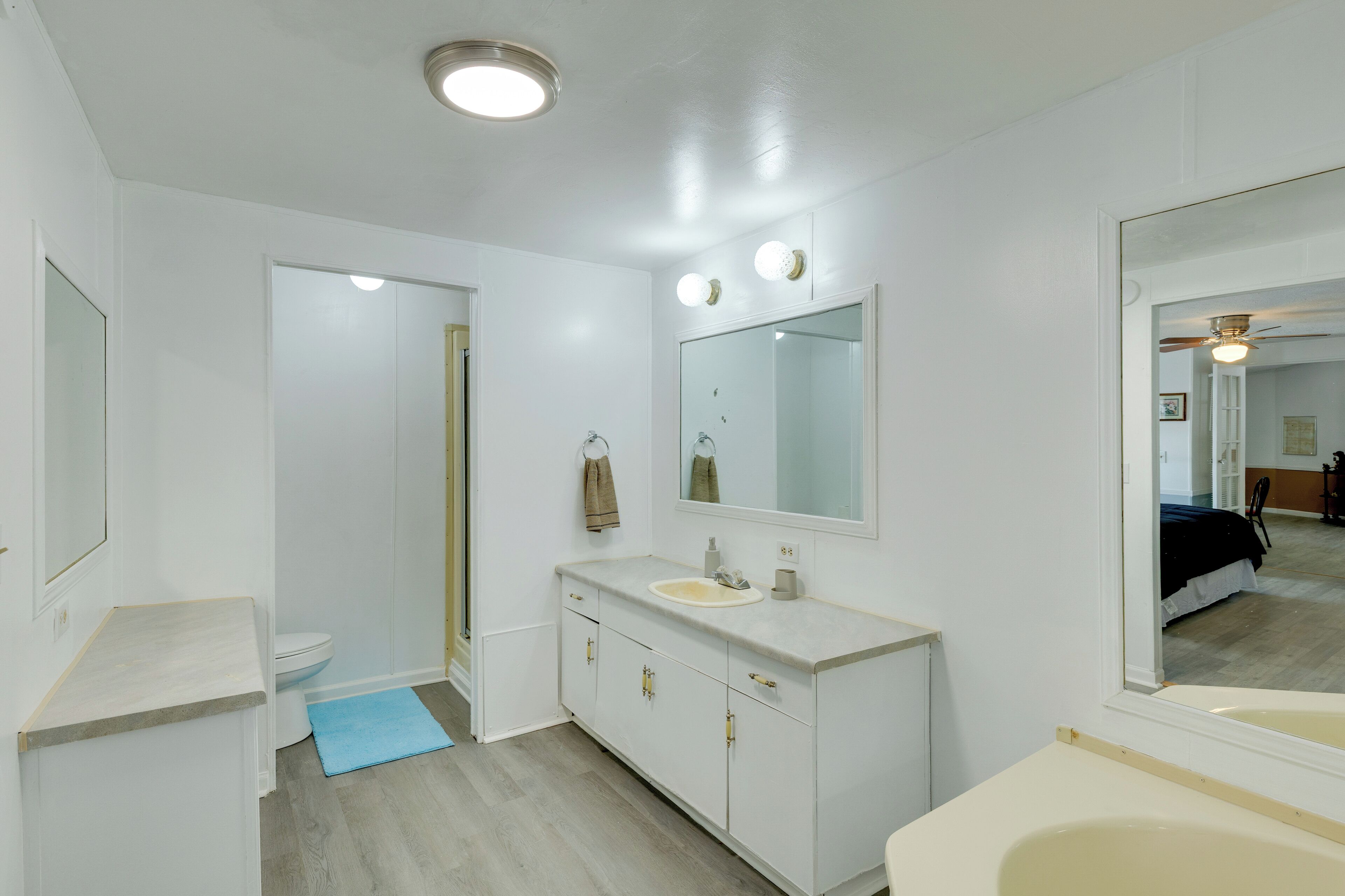 A bathroom with a toilet, sink, mirror, and shower.