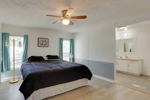 A bedroom with a bed, a ceiling fan, a window with curtains, a bedside table, and a dresser. - Fish & Explore: Wooded Lake Guntersville Retreat (Langston)