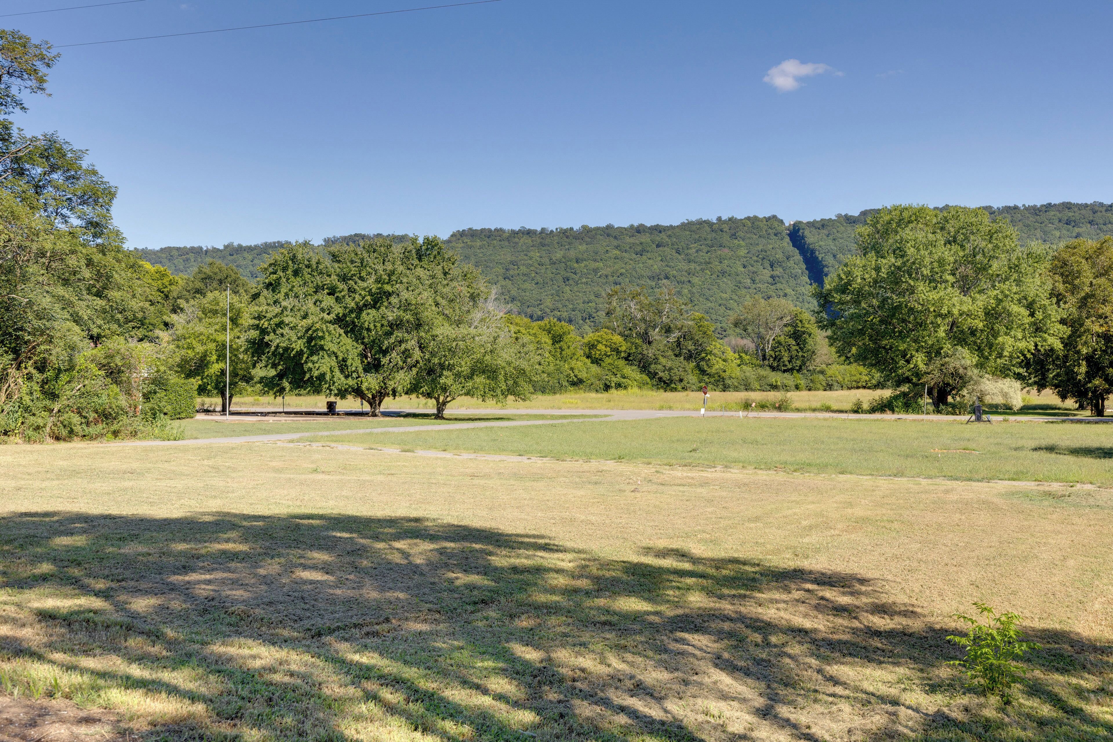 Un parque con un campo cubierto de césped, árboles y una colina al fondo.