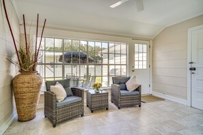 A sunroom with wicker furniture, a large vase with flowers, and a view of the outside. - Sunshine Under the Oak: Baldwin Home w/ Patio! (Baldwin)