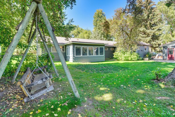 A house with a covered porch, a swing set, and a well-maintained lawn.