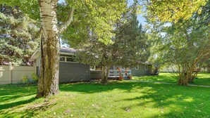 A residential property with a well-maintained lawn, mature trees, and a house with a visible garage.