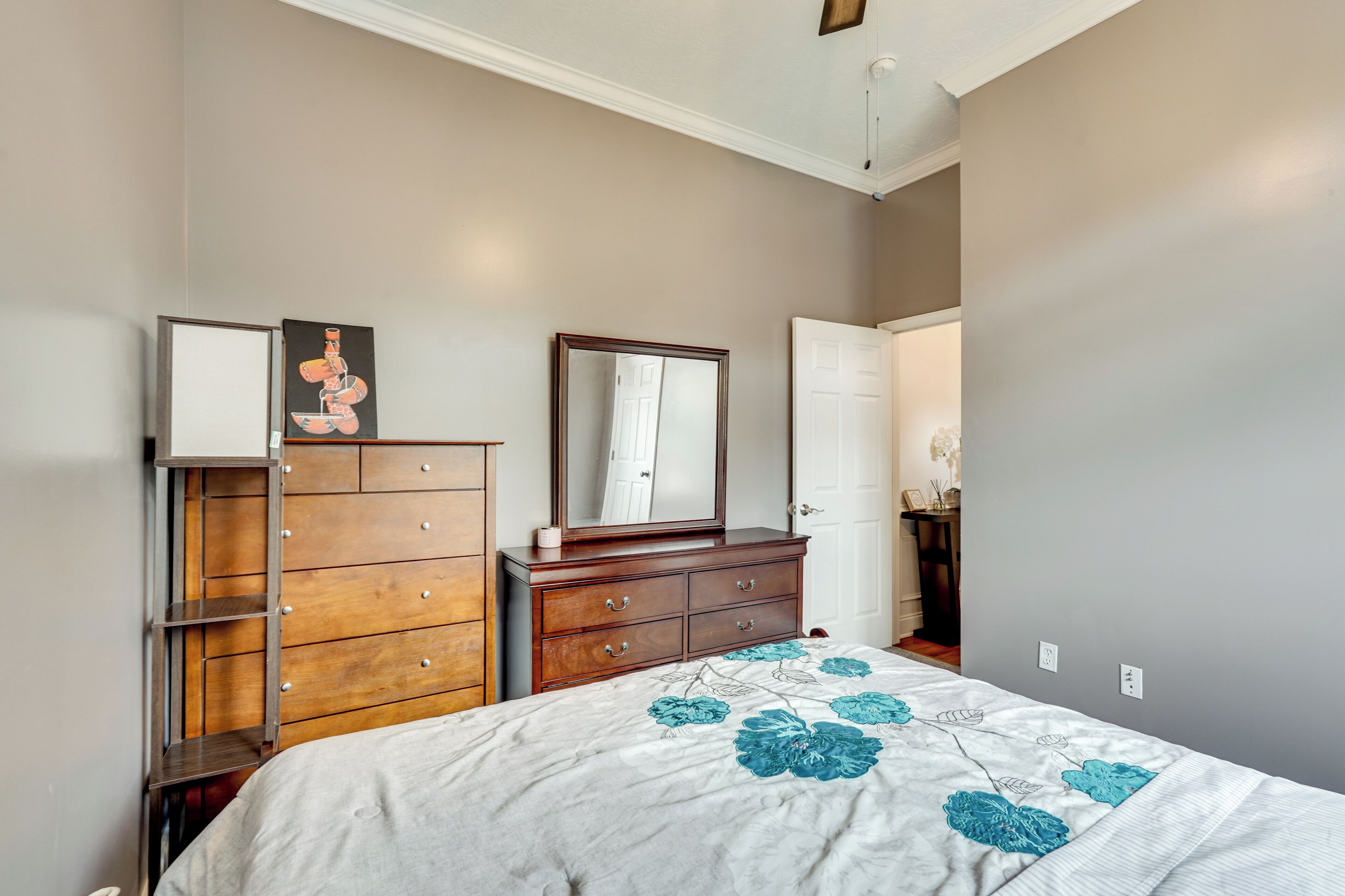 A bedroom with a bed, a dresser, a mirror, and a door.