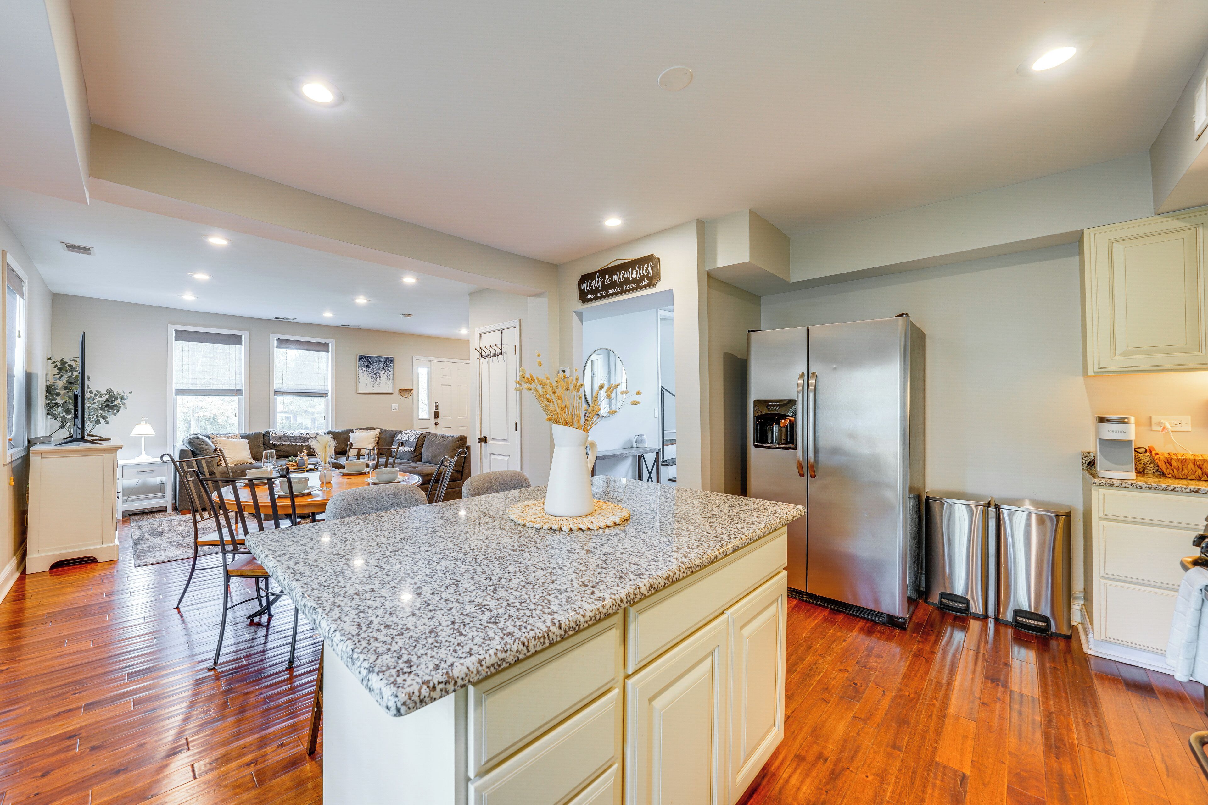 A modern kitchen with a granite countertop, stainless steel appliances, and a dining area with a sofa and chairs.