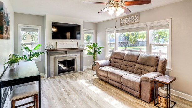 A living room with a fireplace, a sofa, a TV, and a ceiling fan. - Half-mi to Dtwn Yankton & River: Charming Home! (Yankton)