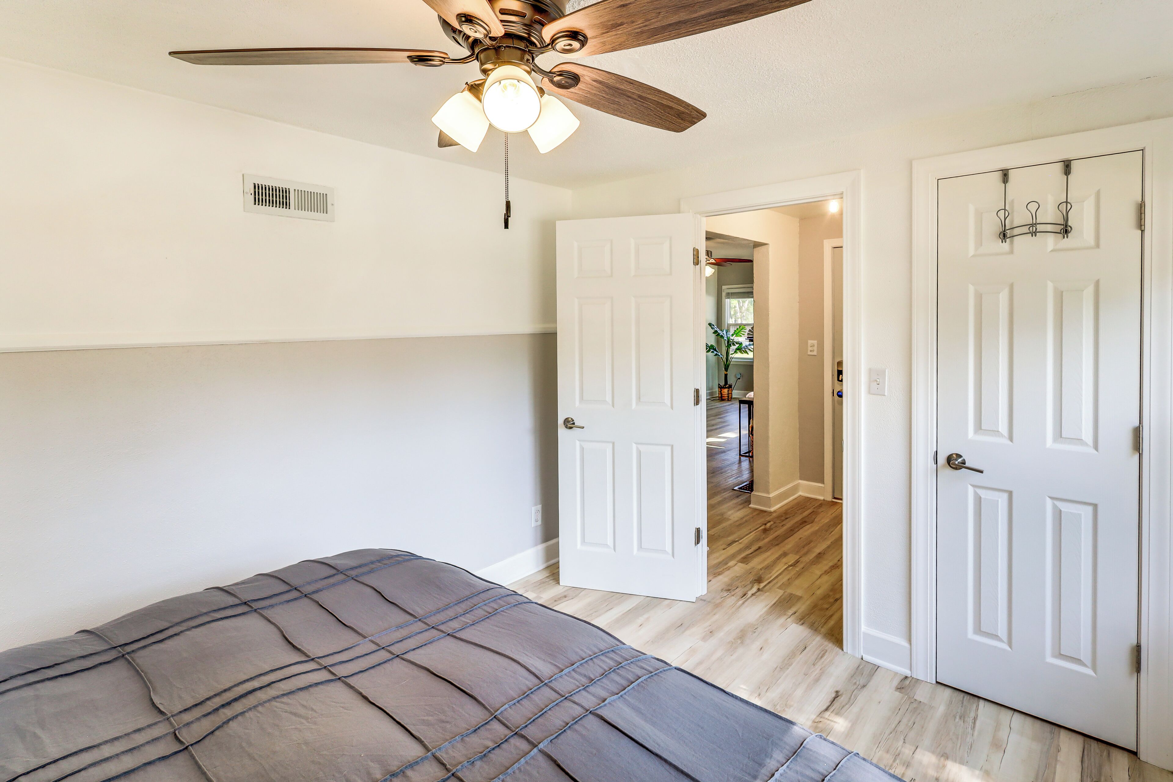 A bedroom with a bed, a ceiling fan, and a door leading to another room.