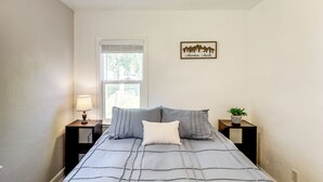 A bedroom with a bed, two nightstands, a lamp, a window, and a wall decoration. - Half-mi to Dtwn Yankton & River: Charming Home! (Yankton)