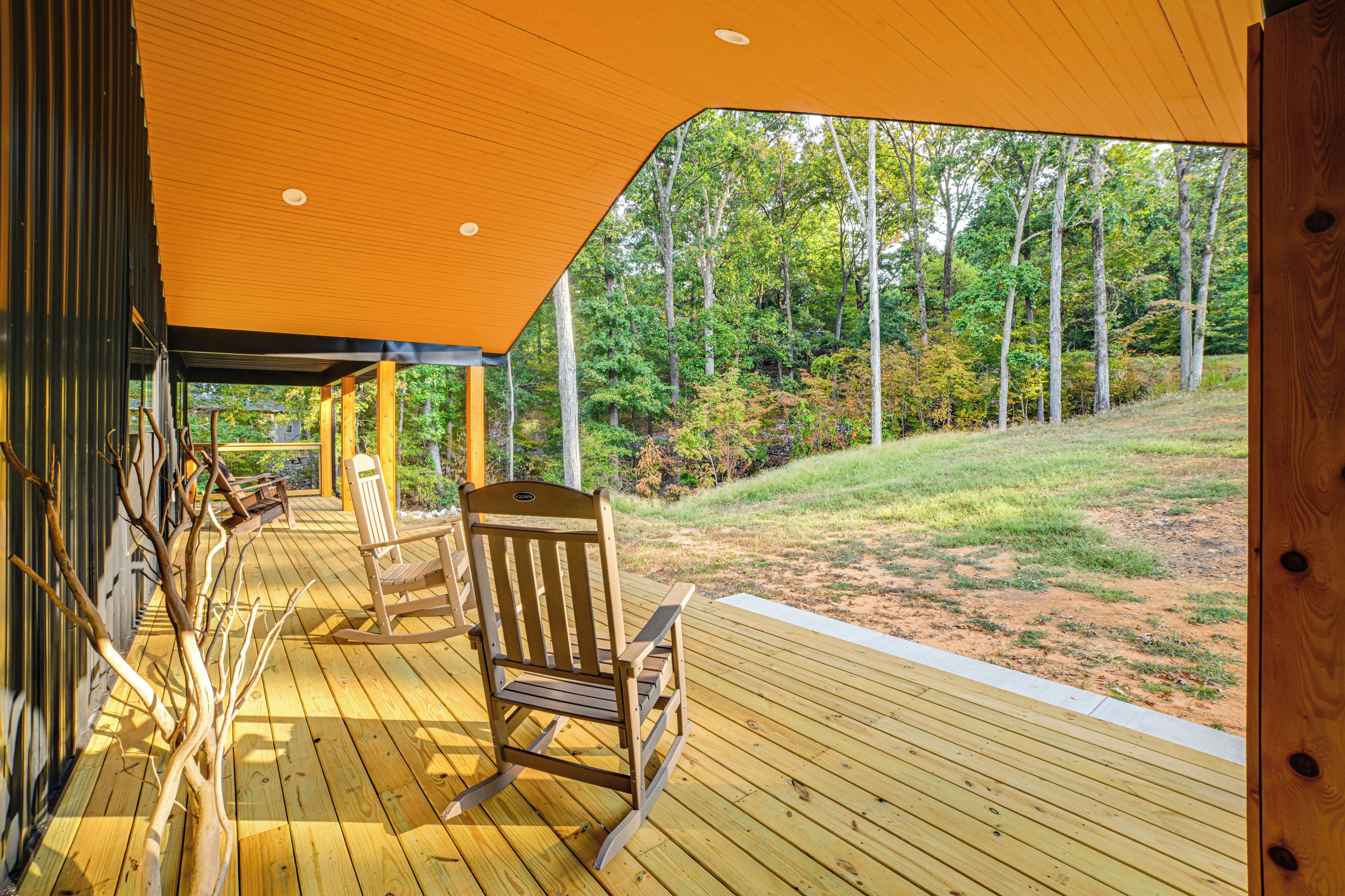 Eine Holzterrasse mit überdachtem Sitzbereich mit Blick auf eine bewaldete Landschaft.