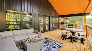 A covered outdoor deck with a sofa, tables, and a ceiling fan. - Private Beach on Lake Barkley! Scenic Family Oasis (Cadiz)