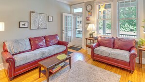 A living room with two red leather sofas, a wooden coffee table, and a door leading outside.