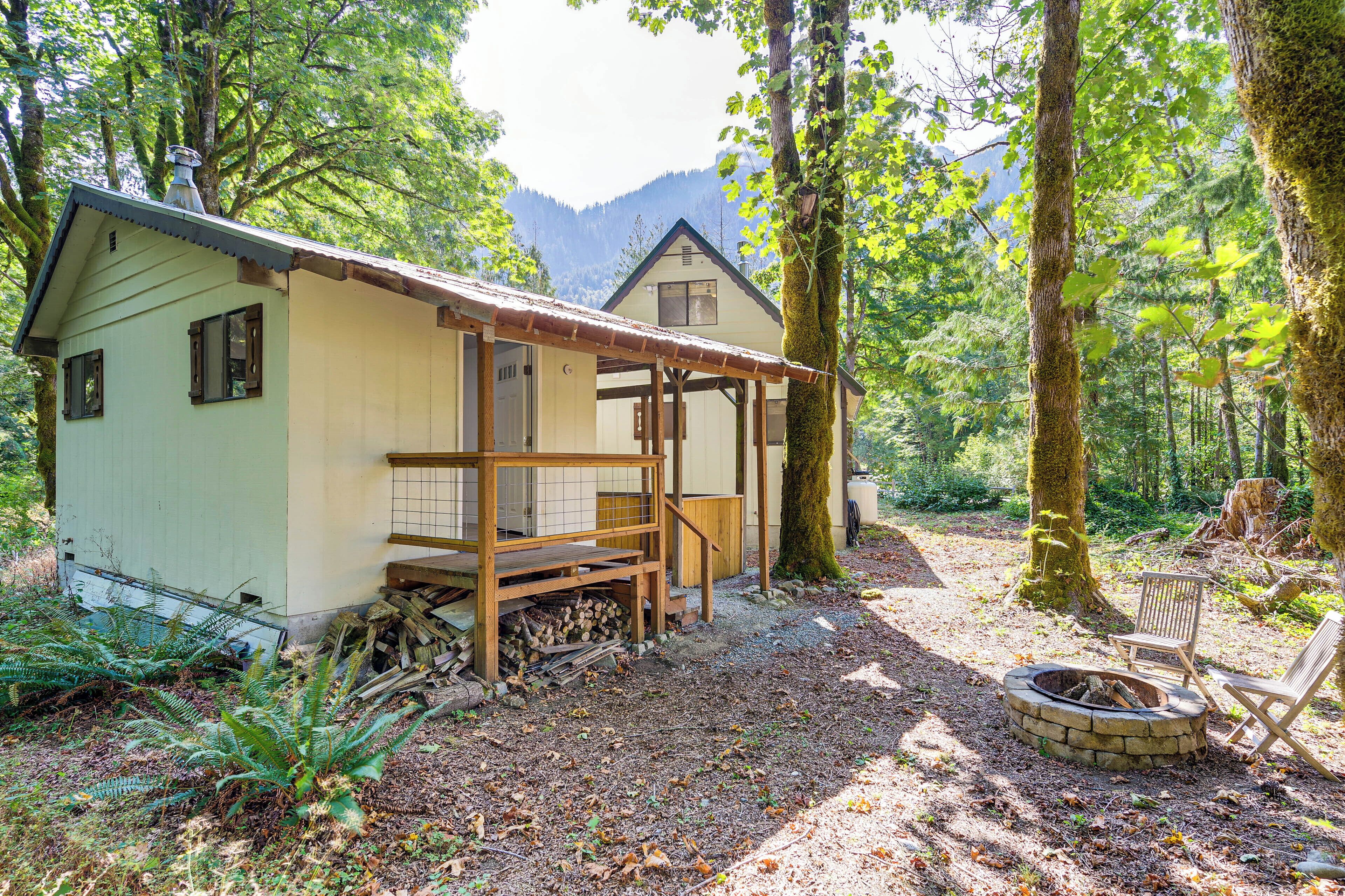 Una cabaña rústica con un porche de madera, un hogar a leña y una silla.
