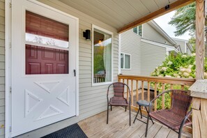 A porch with two wicker chairs, a white door with a garage door, and a wooden railing. - Mtn Views, On-site Trails! Spacious Bartlett Home (Intervale)